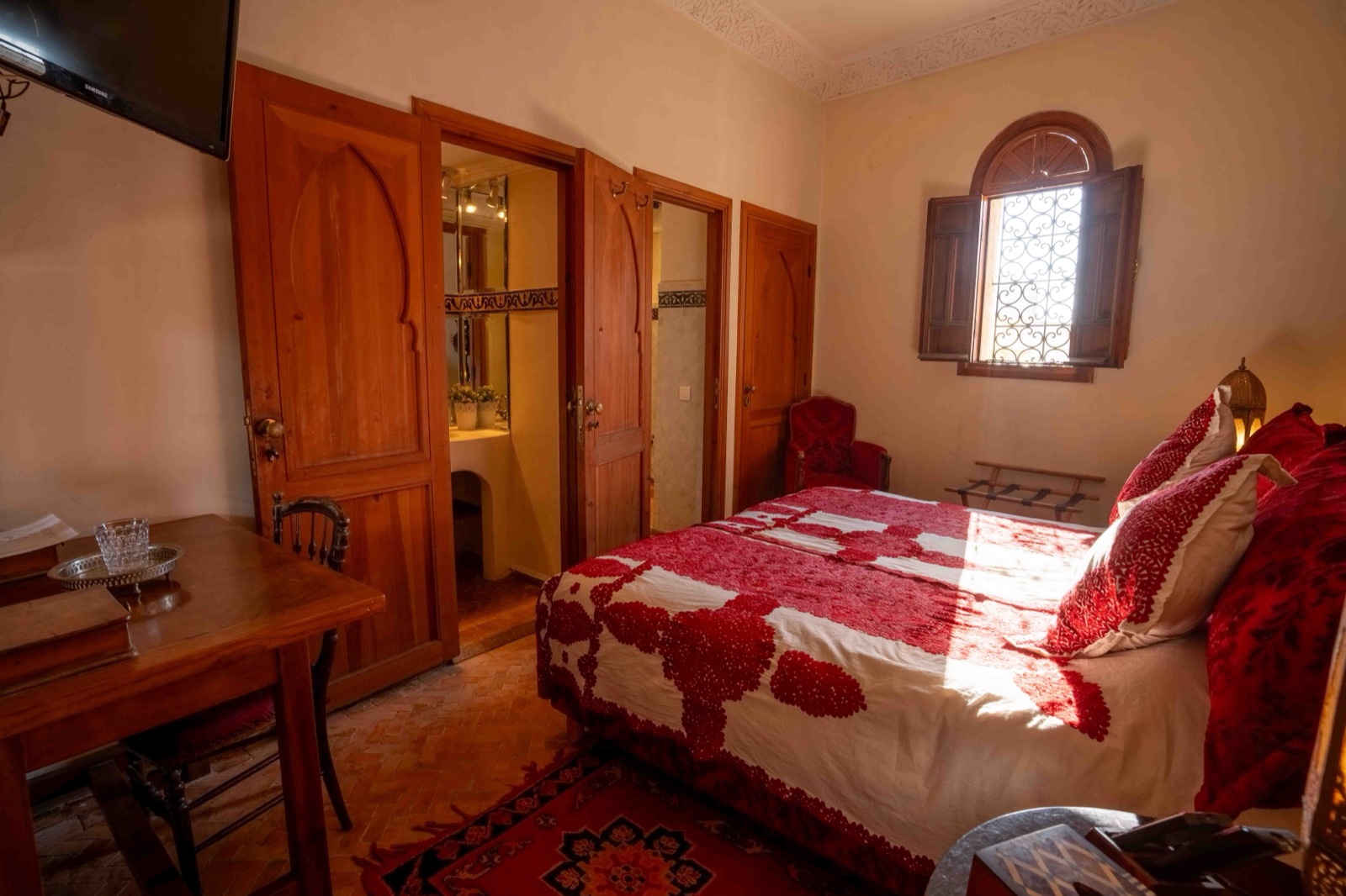 Chambre Fairouz : lit au linge blanc brodé de rouge et fenêtre en arc à volets de bois
