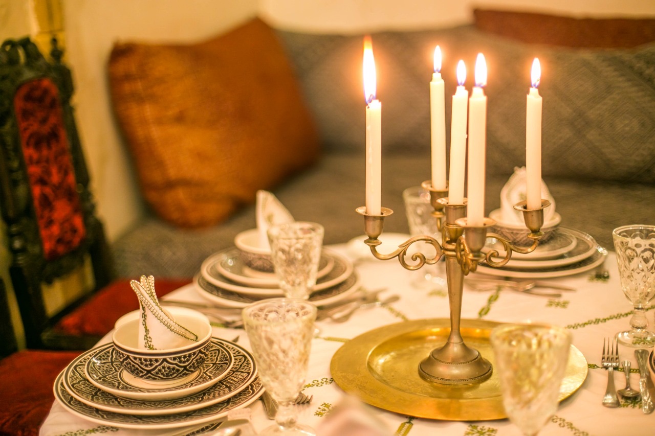 Table dressée aux chandelles : chandelier en laiton, vaisselle peinte et verres ciselés